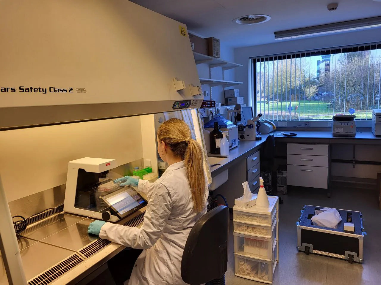 A ReWrite scientist working at a biosafety cabinet in the lab